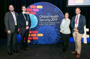 Adam Kamradt-Scott, Felix Rothery, Rebecca Katz, and Matthew Boyce smile on stage at the first International Global Health Security Conference